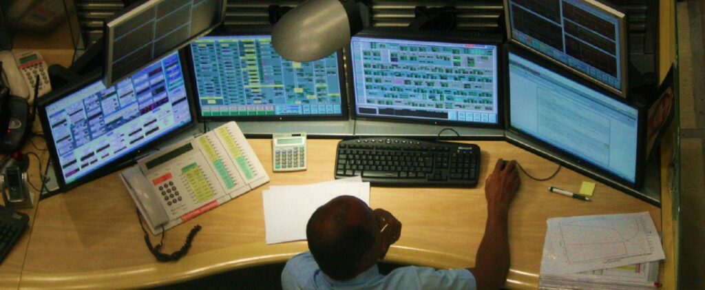 Employee monitoring four computer screens